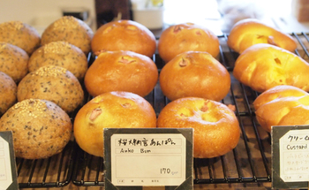 大人気の看板メニュー「桜大納言あんぱん」。あんこも小豆からじっくり煮た本格派で、塩漬けにした桜をあんこに練り込み、甘さと塩気のバランスが絶妙な一品。両隣は、ごまの香ばしさがくせになるごまあんぱんとほっとする味のクリームパン♪