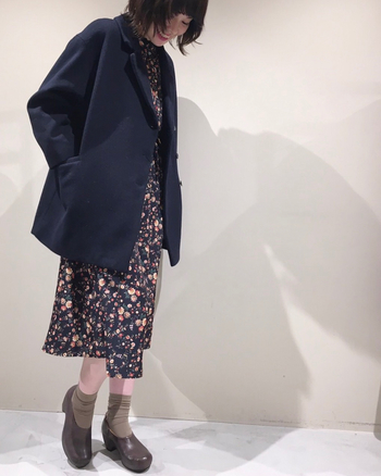 花柄のワンピースに、ネイビーのジャケットを合わせたコーデ。ワンピースとジャケットの色を合わせることで、大人かわいい着こなしに。