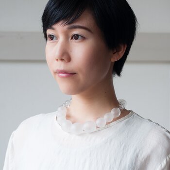 パールのような上品なデザインが印象的な「SPHERE」シリーズのジュエリー。こちらの作品は、日本に2人しかいないひょうたん型の砂時計職人の手で、ひとつひとつ製作されています。クリア×マットなガラスの組合せが美しいSPHERE SATINと、ガラスに縦縞模様を描いたモダンなSPHERE STRIPEの2種類のジュエリーを展開しています。(写真のネックレスはSPHERE SATIN)