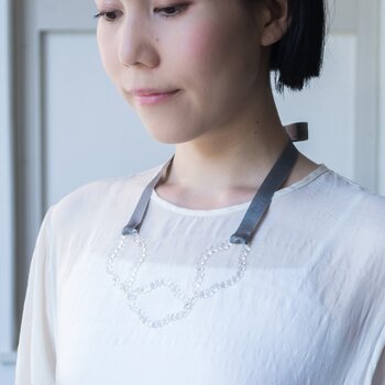 まるで水の雫を連ねたような、繊細でユニークなデザインが魅力的なDOTS Collection。こちらはガラスでできた3つの円に、リボンを組み合わせたおしゃれなネックレスです。小さなガラスの球体一粒一粒に光が反射して、動くたびにキラキラと美しい輝きを放ちます。シーンやコーディネートに合わせて、リボンの長さは自由に調節できますよ◎。