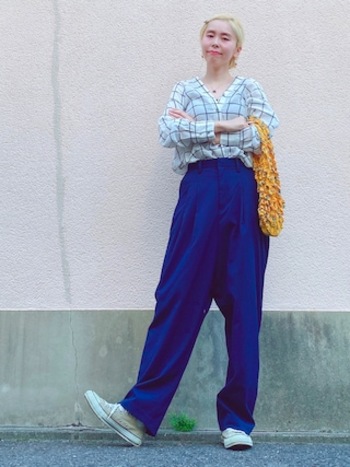 リラクシーなシャツに流れるようなシルエットのコバルトブルーのパンツ。ツヤ感あるスタイルに、ベージュの『オールスター』を合わせてヘルシーに。イエローのバッグを差し色に入れたところも巧みです。