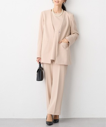やや着丈が長めのノーカラージャケットにセンタープレスパンツを合わせて、スタイリッシュにまとめたコーディネート。インナーも含めてワントーンにしたことで、落ち着きある雰囲気に。淡いピンクベージュに小物のブラックが効いています。
