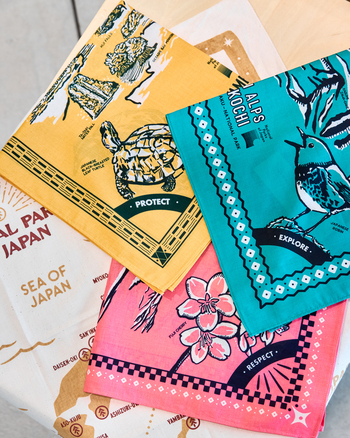 普段アウトドアとは無縁のスタッフも「この機会に！」と購入したバンダナ。イエローはやんばる国立公園、グリーンは中部山岳国立公園、ピンクは富士箱根伊豆国立公園のもの。万博を散策する日除けアイテムとしても活躍してくれました！