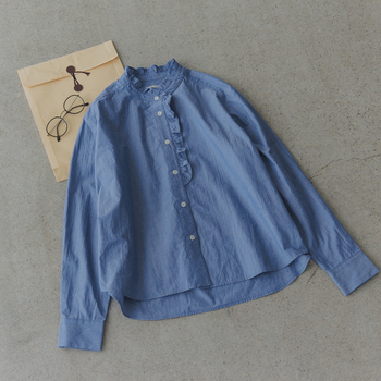 洗いをかけたタイプライター生地に、襟元や前立てにフリルをあしらったシャツ。裾のラウンドヘムや細めのカフスで、甘さを抑えたデザイン。MidiUmiならではの上品なブルーが差し色になり、お仕事シーンにも取り入れやすい一枚です。