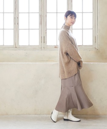 清涼感のある白のロングブーツは、ゆったりめのニットとロングスカート、いずれもベージュトーンでまとめてしっとりと。足元の白が、秋冬コーデを軽やかに演出してくれます。