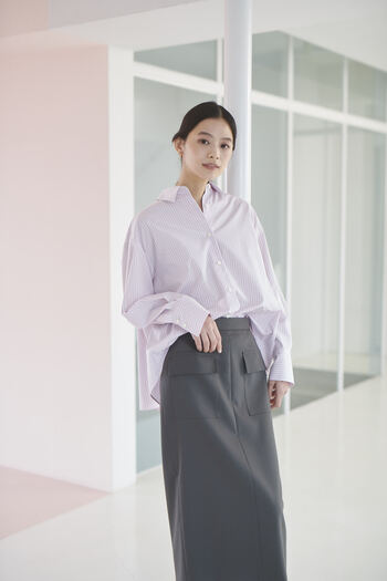 裾にかけて広がりのあるデザインがシンプルでありながらエレガントな雰囲気がある、ピンクベースのストライプシャツ。2ポケットがアクセントのタイトスカートで程よくマニッシュに。