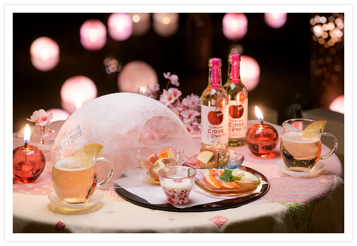 「春待ち桜あかりテラス」の特別席は1日2組限定。この花明かりの空間の中で味わえるのが「雪どけアミューズ」です。津軽で古来から続く雪中貯蔵の風習を生かして作られた「雪室りんご」は、雪の中で熟成し、糖度を増してみずみずしい食感に。このりんごを使った4種のアペリティフとホットシードルを、津軽びいどろの器で楽しめます。