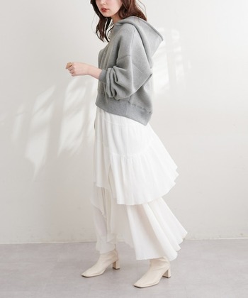 コンパクトなパーカーはボトムスにボリュームのあるものを合わせると華奢な印象に見えます。白いアシンメトリーなスカートでフェミニンに。さらにアイボリーのブーツを合わせると女性らしさ満点です。