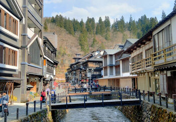 緑に囲まれた銀山温泉。中央を流れる銀山川の両岸に沿って、大正末期から昭和初期に建設された歴史ある木造の宿が軒を連ねています。
