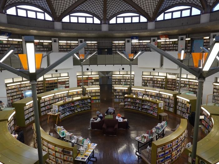 海外のような雰囲気の建物が素敵な「水戸市西部図書館」。映画「図書館戦争」のロケ地として人気のスポットです。建築家・新居千秋氏によってデザインされ、建築界の芥川賞として知られる「吉田五十八賞」を受賞しています。

中央が吹き抜けで2階の壁面が書架になっています。約10万冊の本が丸く囲むようなつくりは、まるでサン・ピエトロ広場の大回廊を彷彿とさせる空間に。デザイン性の高い図書館ですが、落ち着いた雰囲気が漂っています。2階にはソファーもあるので、気になった本があればゆっくりと読書を楽しみましょう。