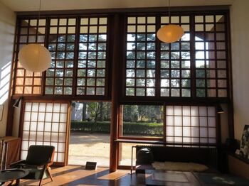 この家最大の見所は、家の中心にあるリビングでしょう。大屋根中央部分の真下に当たる天井の最も高い場所を二層吹き抜けのリビングとし、両脇に書斎、女中部屋と寝室、台所、浴室などを配しています。
高窓の下部に入れられた障子や壁に配された地袋など、モダニズムの造形の中にも和の要素が見られます。

南側の壁は上から下まで丸ごと窓になっているので、非常に解放感にあふれた明るい空間になっています。大きな窓から光が入り、その明るさは想像以上です。和紙を使った照明は彫刻家、イサム・ノグチのデザインです。