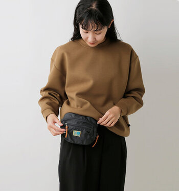 シンプルデザインのウエストバッグは、男女を問わず幅広い層に人気のアイテムです。ベージュのスウェットと黒のパンツを合わせたカジュアルコーデにプラスして、ウエストマークの役割をバッグにお任せ♪