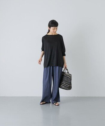 ゆったり感のある黒Tシャツ×ジーンズのカジュアルスタイル。広めのネックラインが女性らしい印象で、デコルテをきれいに見せます。足元は黒のフラットサンダルで抜け感を加え、初夏らしい着こなしに。